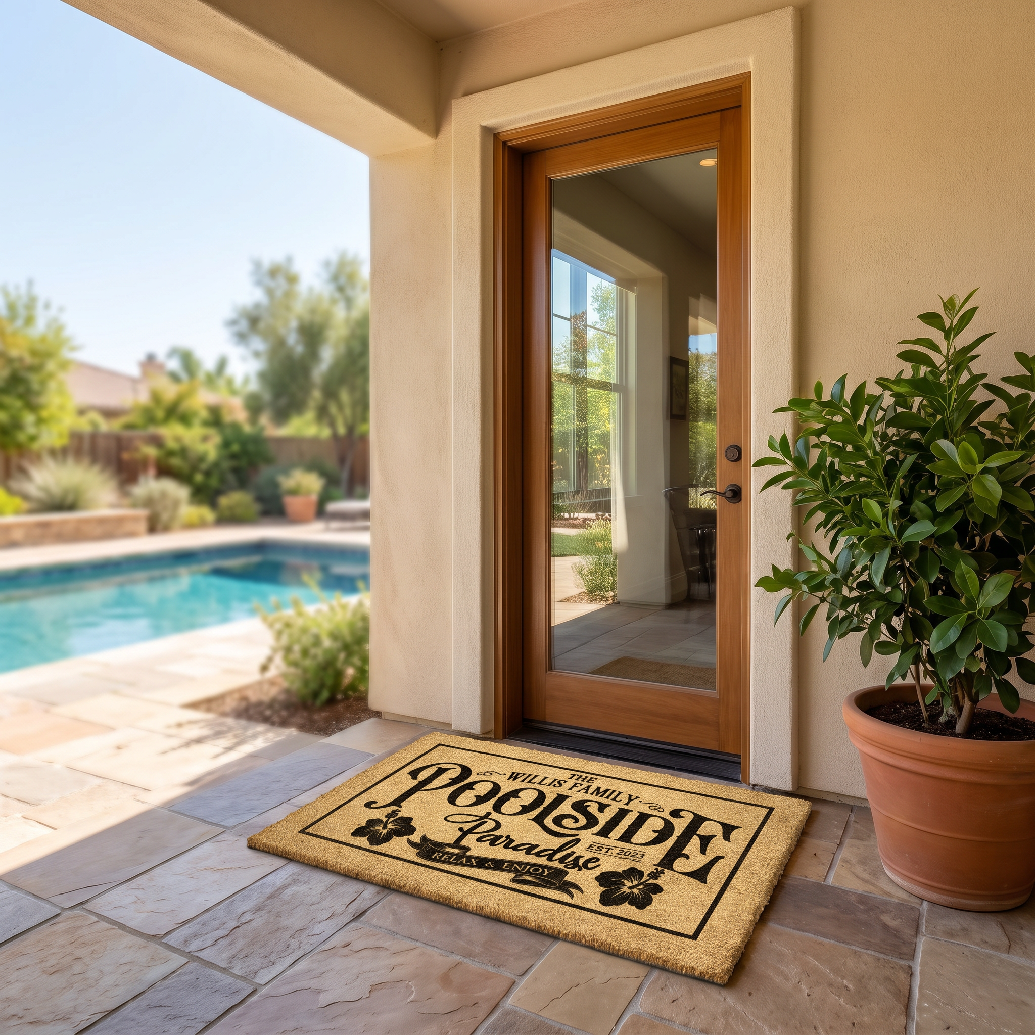 Pool doormat reading Poolside Paradise with a family name and hibiscus, on a patio beside a swimming pool