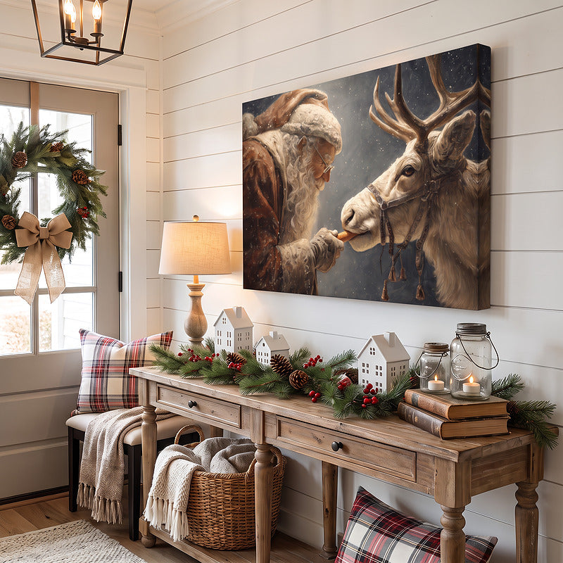 Santa and reindeer painting on unframed canvas in an entryway with a lamp, ceramic village houses and a wreath