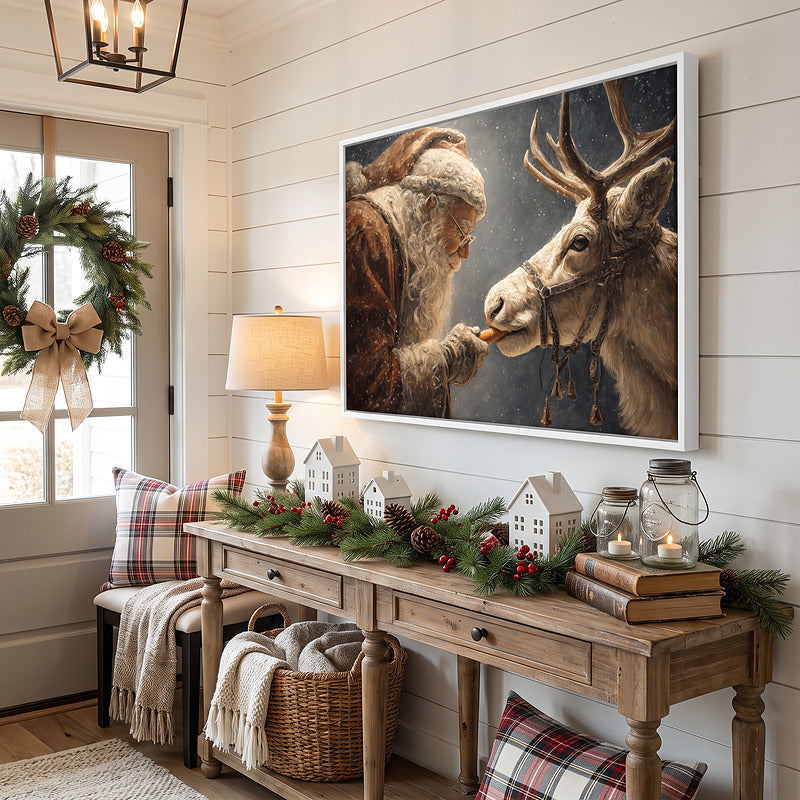 Santa and reindeer canvas in a white frame in an entryway with a lamp, ceramic village houses and a wreath on the door