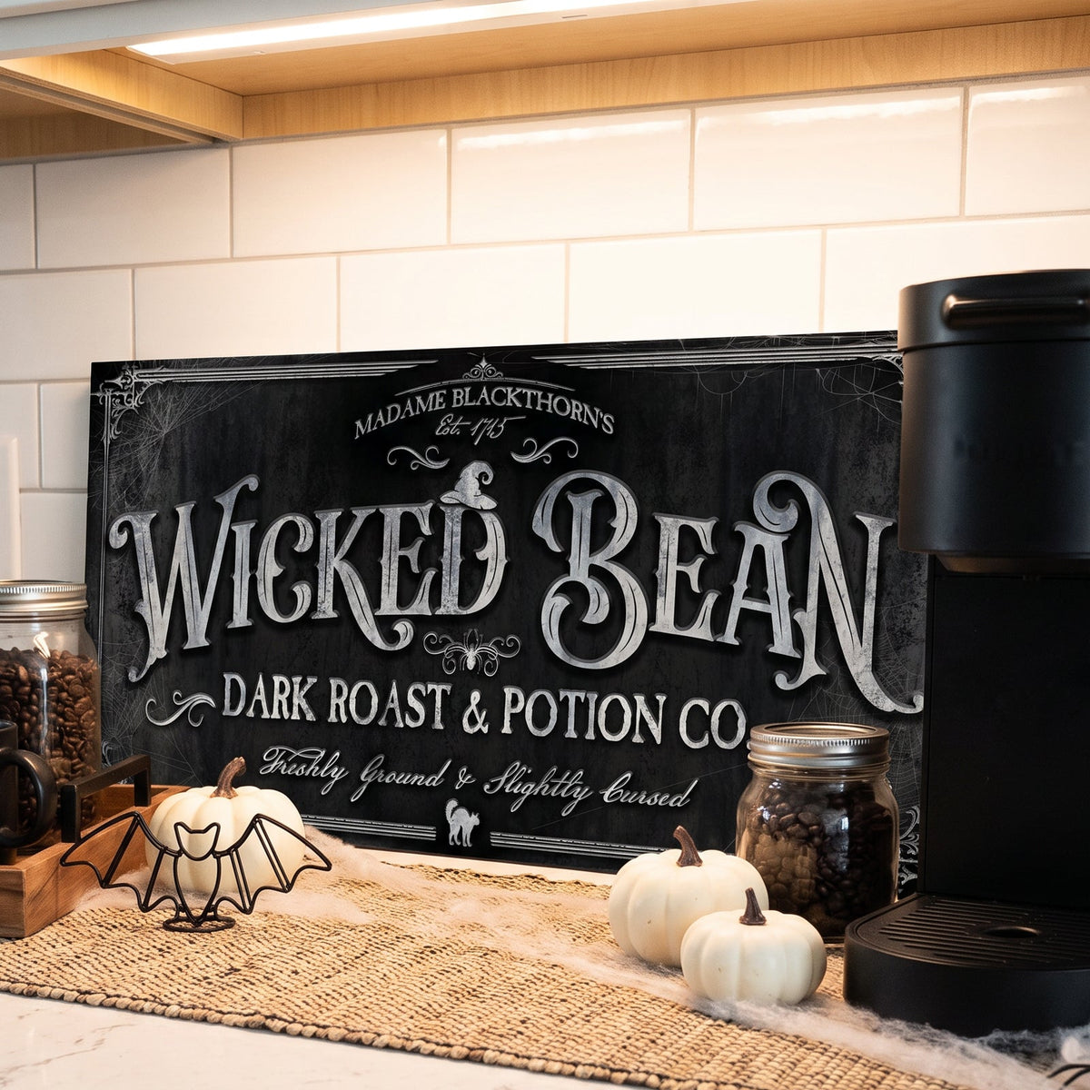Spooky kitchen coffee sign close up on a tiled backsplash with a bat decoration, cobwebs and a jar of coffee beans