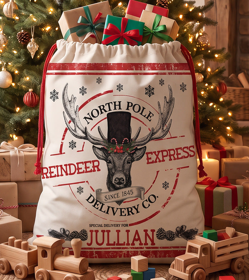 Personalized Santa sack with an engraved North Pole Reindeer Express stag in a top hat, standing beside a Christmas tree