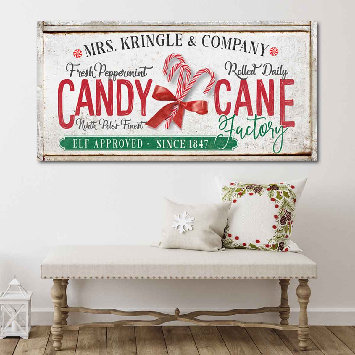Christmas Wall Art on antique faux wood frame with the words [Mrs. Kringle & Company Candy Cane Factory] with large candy canes and red ribbon and a green label that reads [elf approved since 1847]